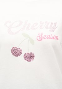 Λευκό ύφασμα με ροζ κείμενο από στρας "Cherry Season" και δύο κεράσια από στρας με πράσινους βλαστούς και φύλλα κάτω από το κείμενο.