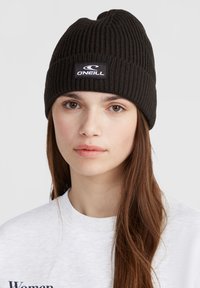 Beanie a coste nera realizzata in materiale knit, con un'etichetta rettangolare bianca contenente il testo "ONEILL" sulla parte frontale.