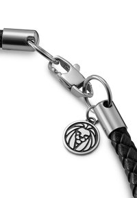 Sort fletlæderrem med sølvfarvet metalhardware, udstyret med en klo spænde og et graveret rundt charms med et løvedesign.