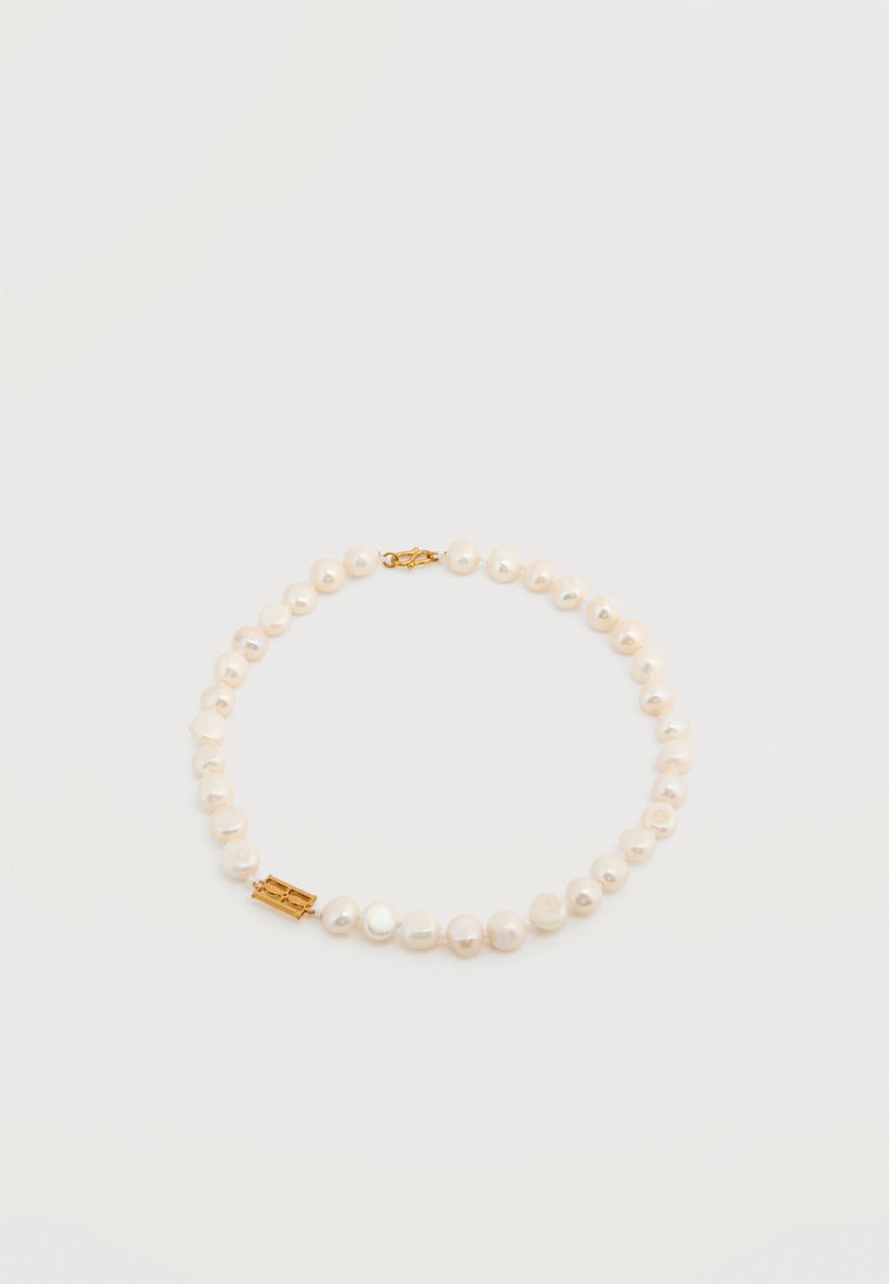 Χάντρες λευκών ακανόνιστων μαργαριταριών με χρυσή αγκράφα σε απλό φωτεινό φόντο.