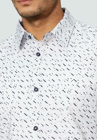 Witte shirt met een zwart abstract patroon, met een button-down kraag, zwarte knopen en een borstzak, gemaakt van lichtgewicht stof.
