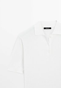 Polo blanc à manches courtes avec col et trois boutons, avec une étiquette Massimo Dutti à l'intérieur de l'encolure.