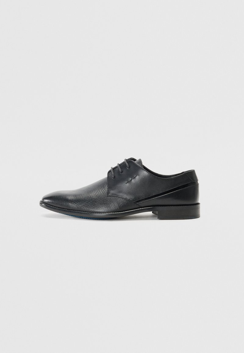 Chaussure noire en cuir avec un bout pointu, présentant un design texturé et des accents de panneaux lisses. Comprend cinq œillets pour les lacets.