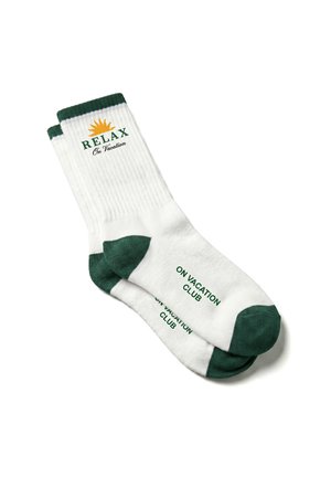 Chaussettes blanches hautes avec les orteils et bords verts, avec les textes "RELAX On Vacation" et "ON VACATION CLUB" et un graphique de soleil jaune à la cheville.