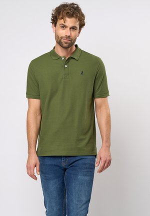 Olive green polo shirt made of textured fabric, featuring a collar, three buttons, and a small navy logo on the left chest.