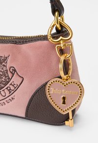 Ροζ και καφέ τσάντα, φτιαγμένη από suede και υφασμάτινο δέρμα. Διαθέτει χρυσό υλικό, κλείσιμο με φερμουάρ και μια καρδιά-σχήματος ετικέτα.