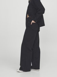 Black corduroy shirt and wide-leg pants, featuring a relaxed fit, front pockets, and classic button details, paired with black sneakers.