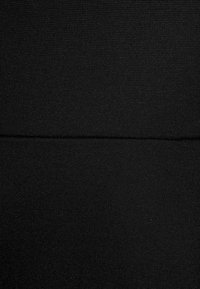 Czarna tkanina o miękkiej, dzianinowej strukturze. Widoczne detale szwów, tworzące efekt podziału na dwie części. Gładka, jednolita powierzchnia.