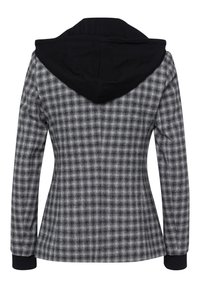 Veste à carreaux gris avec une capuche noire. Coupe ajustée, manches longues et poignets côtelés. Le tissu a une texture lisse avec un motif à carreaux.