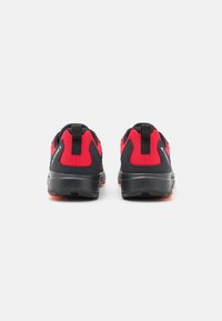 Rote und schwarze Sportschuhe mit Mesh-Obermaterial, gepolsterten Sohlen und Zuglaschen an den Fersen. Strukturierte Materialien und robustes Profil.