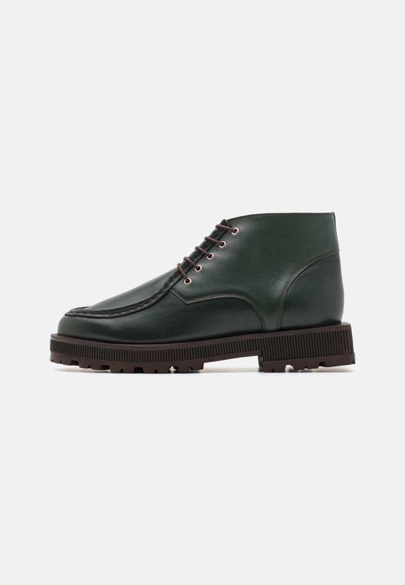 Green leather ankle boots with a round toe, brown rubber sole, and metal eyelets. Smooth texture with subtle stitching details.