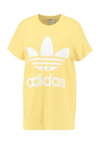 Yellow cotton t-shirt with a round neck, short sleeves, and a large white Adidas logo featuring three stripes and an iconic leaf design.