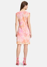 Robe à manches courtes en tissu léger et fluide avec un motif tie-dye orange et rose. Présente une silhouette légèrement évasée et une coupe au genou.