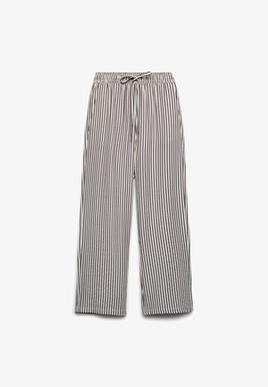 Pantalon blanc ample avec fines rayures verticales noires, taille élastique et cordon de serrage à l'avant.