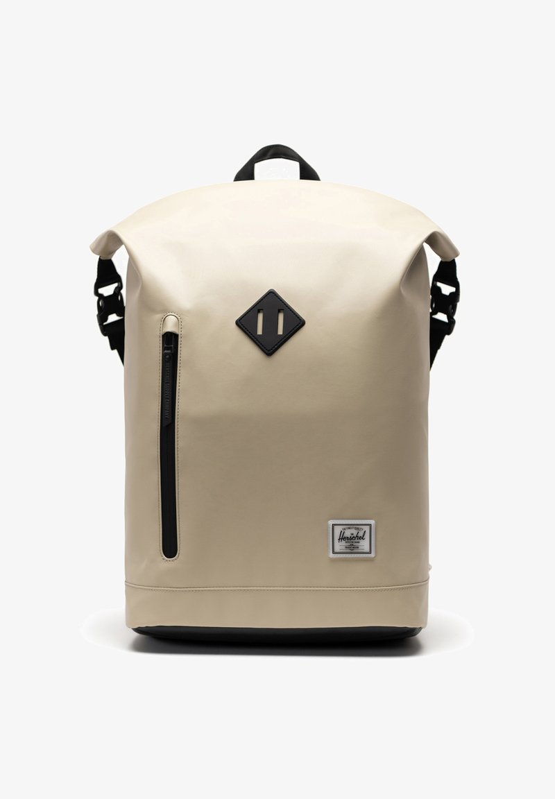 Beige veske som er vanntett med rullesystem, sorte detaljer, en frontlomme med glidelås og et logo-patch nederst.