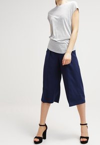 Šedý krátký rukáv top v kombinaci s námořnickými culotami, které mají volný střih. Černé lodičky na kotníkovém pásku dotvářejí celý outfit. Hladká textura látky.
