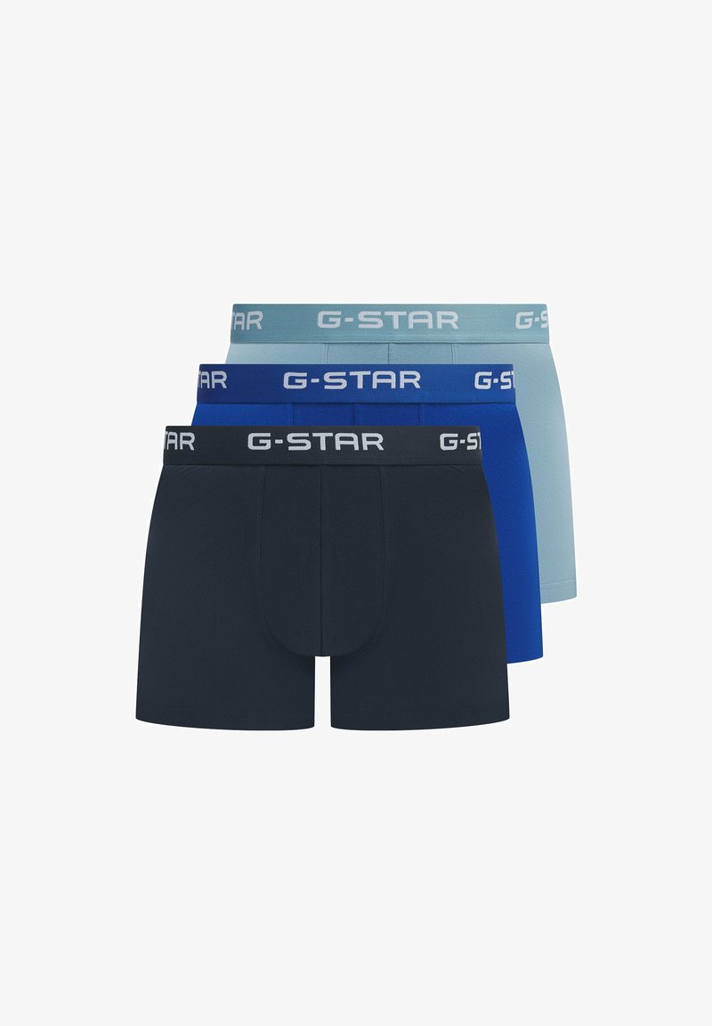 Drei Paare G-Star Boxershorts in den Farbtönen Dunkelmarine, Blau und Hellblau. Jedes Paar hat einen kontrastierenden Logo-Gummibund. Glatte Stoffstruktur.