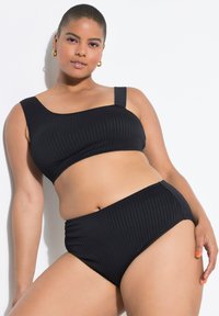 Zwarte geribbelde bikini-top met een dikke band en een hoog uitgesneden broekje met een gestructureerd patroon. Gladde afwerking en aansluitend ontwerp.