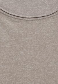 Jasnobeżowa tkanina o miękkiej, teksturowanej powierzchni. Posiada gładki, okrągły dekolt oraz delikatne, prążkowane wykończenia na krawędziach.