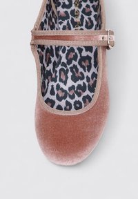 Bailarina de terciopelo rosa con punta redondeada, presenta una correa en contraste de color marrón y un forro de estampado de leopardo. Textura suave, apariencia delicada.