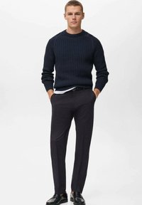 Navy ribbed knit sweater, white undershirt, dark trousers, and black shoes. The outfit features a casual style with a fitted silhouette.