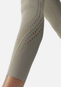 Strak zittende legging in een gedempte olijf groene stof, met een zijontwerp met ronde uitsparingen en een subtiele elastische textuur.