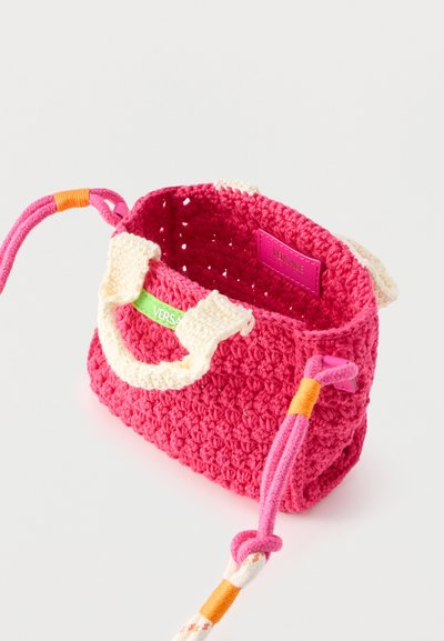 Μικρή ροζ τσάντα χειροποίητη με κρεμ χερούλια, κορδόνια με πορτοκαλί στοιχεία και ορατή ετικέτα Versace στο εσωτερικό.