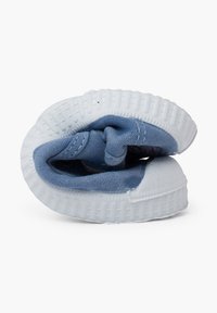 Baskets en toile bleue avec une semelle en caoutchouc texturé blanc, légèrement pliées. Elles présentent un bout arrondi et des détails cousus sur le dessus.