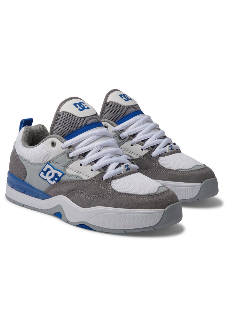 DC Schuhe in Grau, Weiß und Blau. Sie bestehen aus Mesh- und Wildledermaterialien; gepolstertem Zungenbereich; Gummisohle; und einem auffälligen Logo an der Seite.