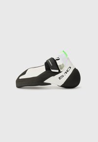 Climbing shoe in white and black with a green accent, featuring a pointed toe, velcro strap, and a rubber sole for grip.