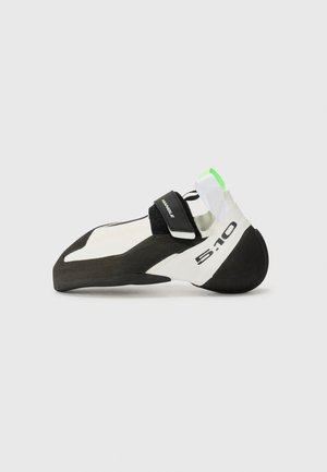 Climbing shoe in white and black with a green accent, featuring a pointed toe, velcro strap, and a rubber sole for grip.