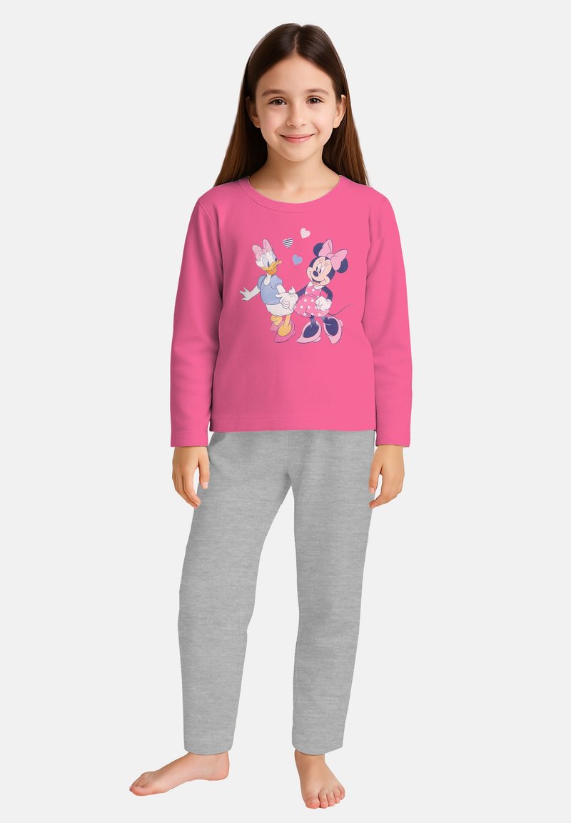 Ragazza sorridente che indossa una maglietta a maniche lunghe rosa con stampa di Minnie e Paperina e pantaloni della tuta grigio chiaro, in piedi a piedi nudi su uno sfondo bianco.