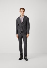 Grå rutete dress med slim fit, ensidig blazer, matchende bukser og en lys lilla t-skjorte under. Svarte loafers fullfører antrekket.