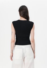 Black ribbed knit sleeveless top with a fitted silhouette. The design features textured stripes and a round neckline.