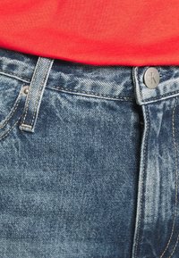 Jeans i denim med en blekt blå tvätt, med en metallknapp med 'CK'-logotyp, kontrasterande sömmar och mid-rise midjeband.