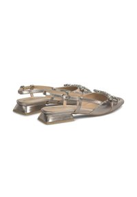 Chaussures à talon bas en bronze métallique avec une bride arrière, strap décoratif avec des gemmes, et texture en cuir lisse.