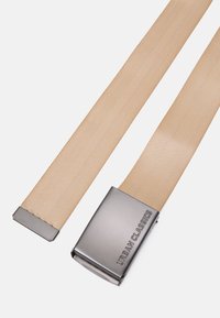 Bežinė elastinga dirželis su matinio pilko metalo sagtimi, kurioje įspaustas užrašas "URBAN CLASSICS"; lygus paviršius su elegantišku, minimalizmo stiliumi.
