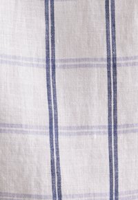 Tissu en lin blanc avec des rayures verticales et horizontales bleu marine formant un motif à carreaux.