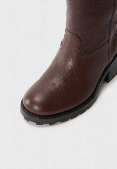 Brown leather ankle boot with a textured finish, rounded toe, and black rubber sole featuring a tread pattern for grip.