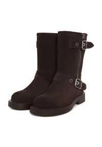 Botine din material maro, până la gleznă, cu închidere cu fermoar, curea cu accent de cataramă și talpă plată robustă. Textură netedă și design simplu.