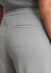 Pantaloni grigi con un tessuto morbido e texture. Presentano una discreta tasca posteriore e una cintura elastica per il massimo comfort. Vista ravvicinata del retro.