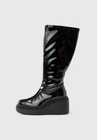 Crna sjajna čizma do koljena s glatkom teksturom, zaobljenim vrhom i debelim potplatom. Ima suptilni valoviti uzorak na štitu.