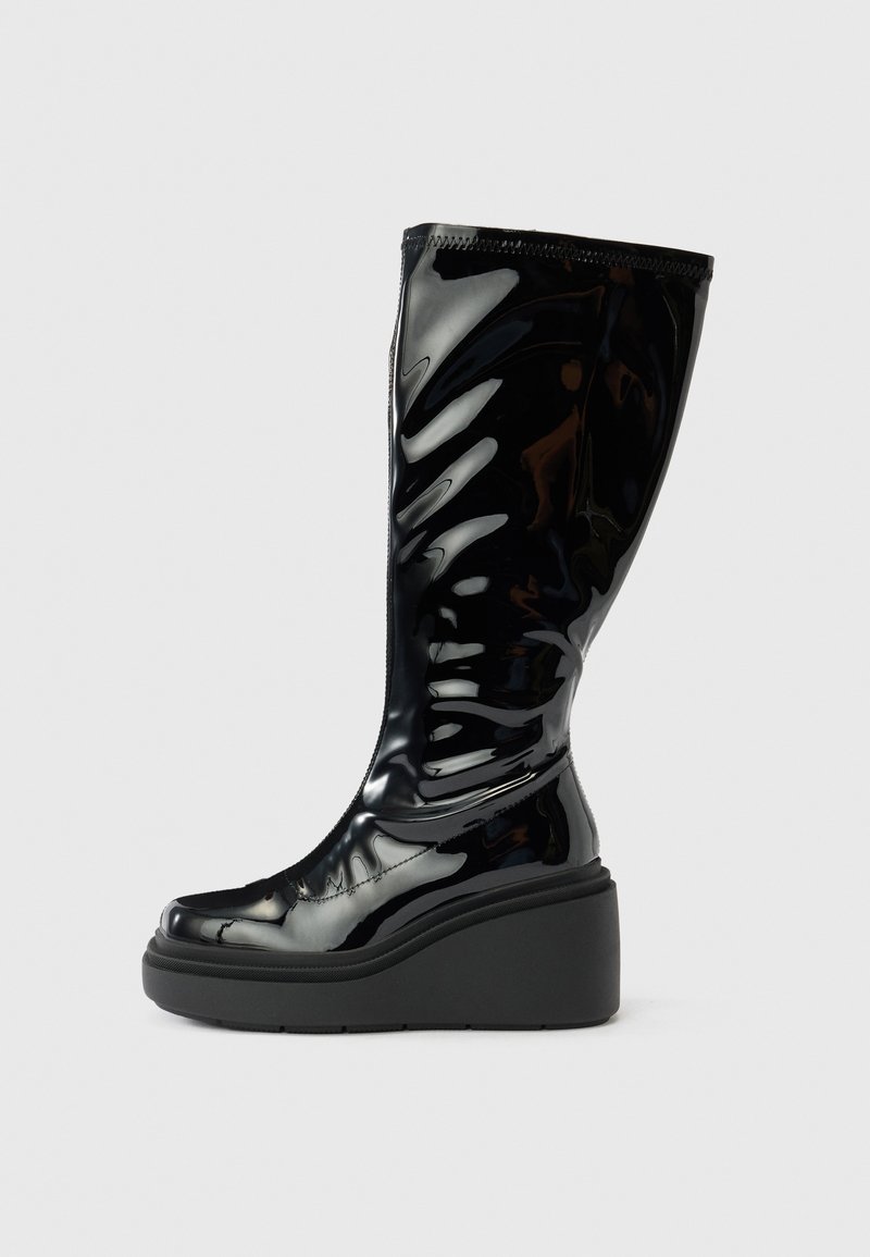 Crna sjajna čizma do koljena s glatkom teksturom, zaobljenim vrhom i debelim potplatom. Ima suptilni valoviti uzorak na štitu.