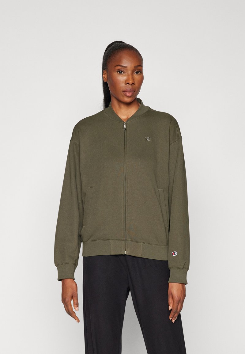 Olivgrüner Reißverschluss-Hoodie mit rundem Kragen, seitlichen Taschen, gerippten Bündchen und Logo auf der linken Brust. Weicher Stoff, lockere Passform.