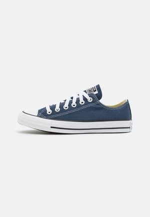 Sneaker en toile bleu marine avec des lacets blancs, embout en caoutchouc et semelle à rayures noires. Design basse et marquage sur la languette.