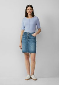 Jasnoniebieski prążkowany top z krótkim rękawem w połączeniu z midi spódnicą dżinsową z guzikami z przodu, kieszeniami bocznymi i postrzępionym dołem. Białe sneakersy.