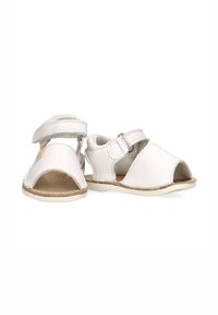 Sandalias de cuero blanco con puntera abierta, correas ajustables y suelas beis. Textura suave y diseño minimalista con bordes redondeados.