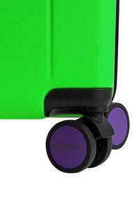 Grüner Hartschalenkoffer mit strukturierter Oberfläche, schwarzen Akzenten und violetten Rollen, auf denen der Schriftzug "ETERNITIVE" zu sehen ist.