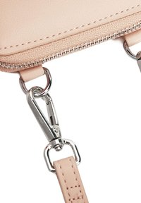 Světle růžová kabelka z faux kůže se stříbrným zipem a kovovými doplňky. Má hladký povrch a odnímatelný popruh s kovovými karabinami.
