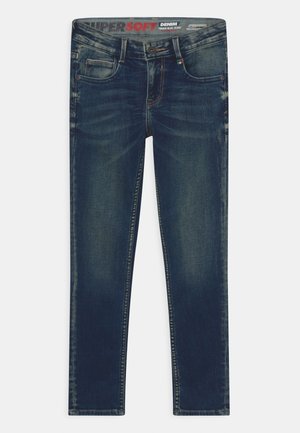 Jean en denim bleu foncé à coupe slim, avec un design à cinq poches, des coutures visibles et une ceinture marquée d'une marque.